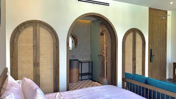 Una habitación de hotel con cama, baño con ducha y zona de estar con vistas.