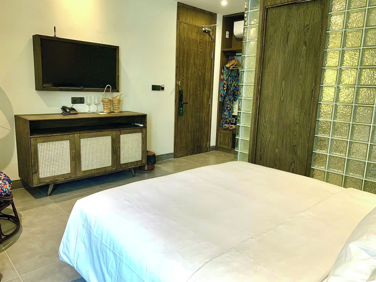 Ein Schlafzimmer mit einem großen Bett, einem an der Wand montierten Fernseher, einem Holzschrank mit Korbwannen und einem Kleiderschrank mit Glastür.