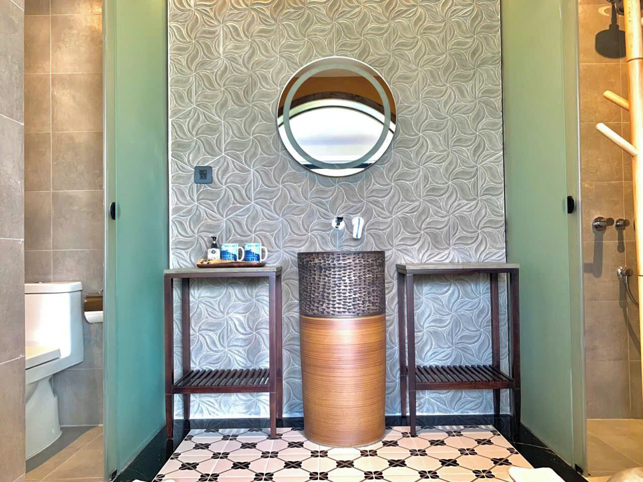 A bathroom with two sinks, a round mirror, and a textured wall.
