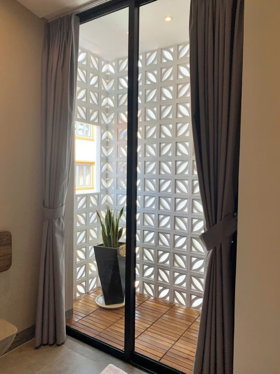 Eine Glastür zur Terrasse, versehen mit einem weißen, geometrischen Gitter und einem Blumentopf, mit Holzboden.