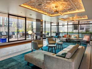 A modern lounge area with a mix of seating options, including sofas and chairs, arranged around a central coffee table. Large windows provide views of the cityscape. - GINZA HOTEL by GRANBELL (Tokyo)