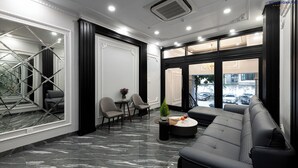 A modern lobby with a marble floor, a black leather sofa, and a small table with a plant and a glass. - Beryl Signature Hanoi Hotel (Hanoi)