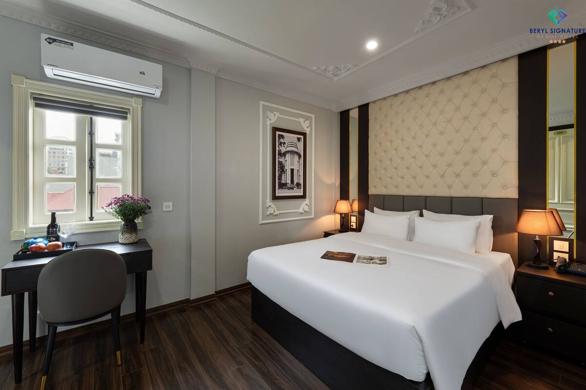 Une chambre d’hôtel équipée d’un lit, d’un bureau, d’une chaise et d’une fenêtre donnant sur la ville.
