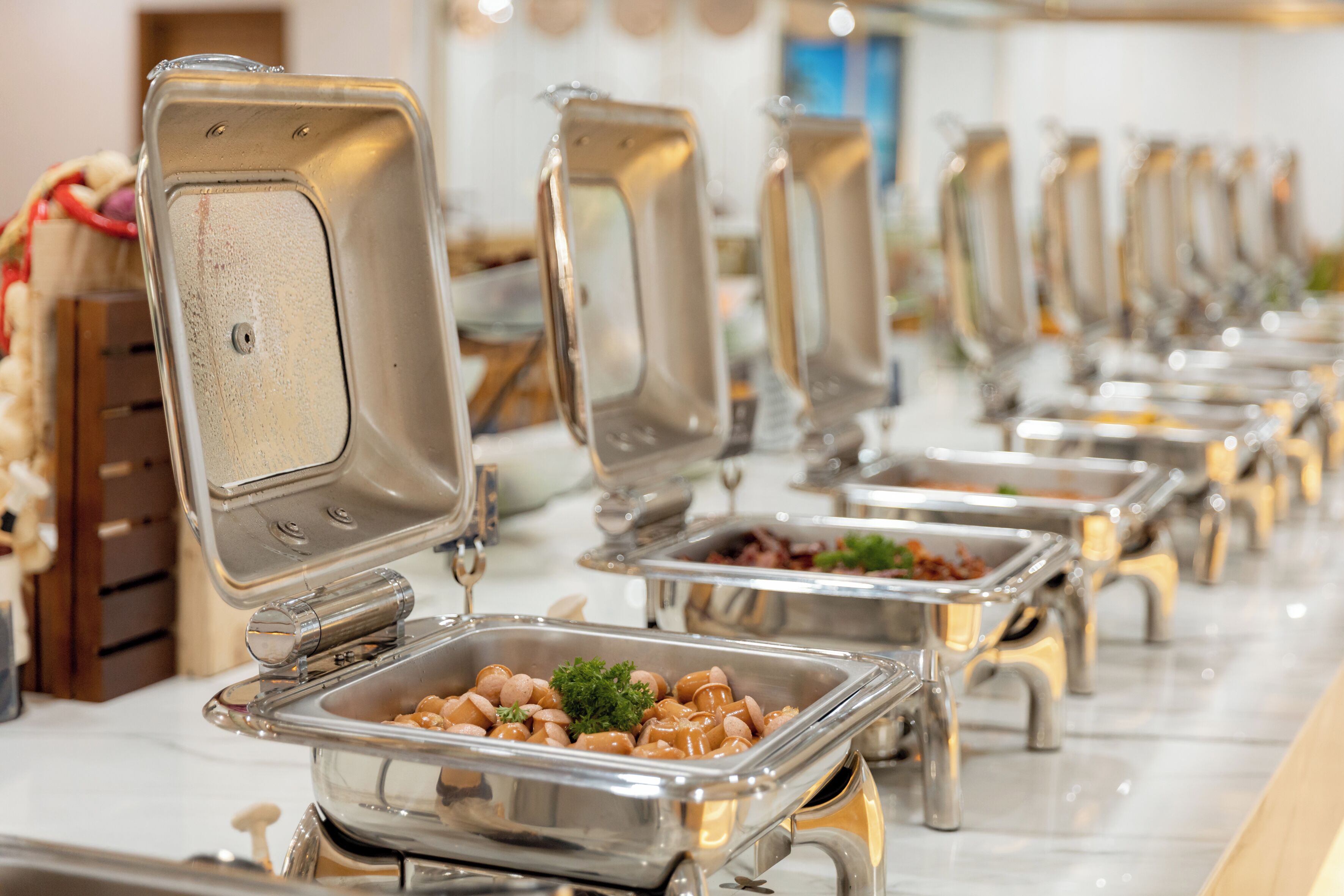 Una barra de buffet con múltiples bandejas de acero inoxidable.