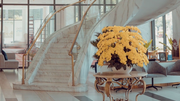 A modern interior with a marble staircase, large windows, and a reception area with a plant. -  Petro House Vung Tau (Block A) (Ho Chi Minh City)