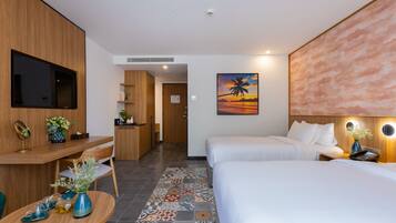 A hotel room with a bed, a desk, a chair, a TV, and a painting of a sunset.