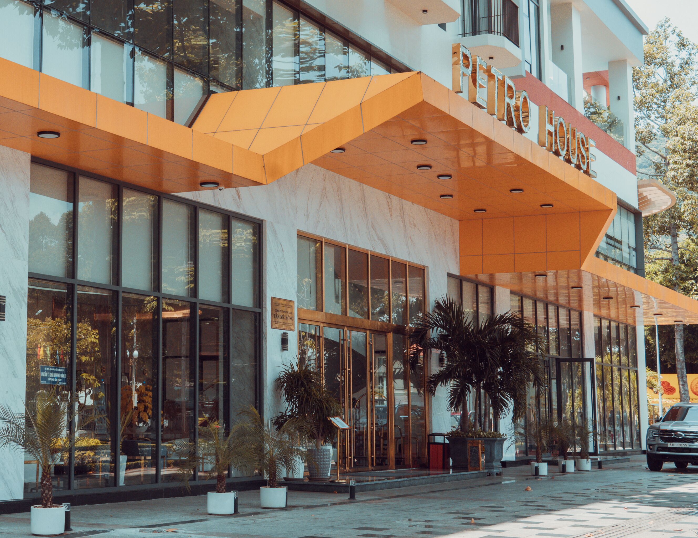 A modern hotel with a prominent entrance, large windows, and potted plants.