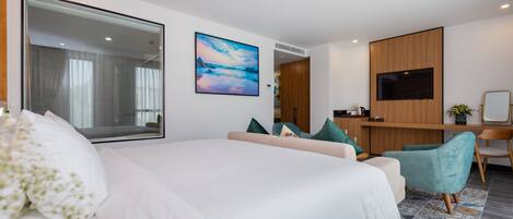 A modern hotel room with a large bed, a desk, a TV, and a view of the bathroom.