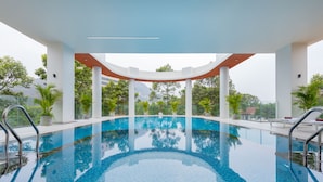 An indoor swimming pool with clear blue water, surrounded by white pillars and potted plants. -  Petro House Vung Tau (Block A) (Ho Chi Minh City)