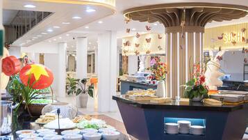 A buffet area with a variety of dishes, a central column with hanging decorations, and a 'SUSHI' sign in the background.