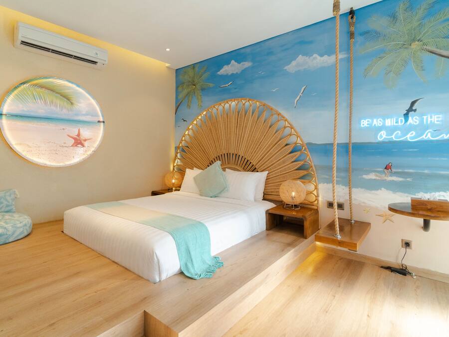 Quarto com um mural com tema praiano, um adorno redondo na parede e uma cadeira balanço.