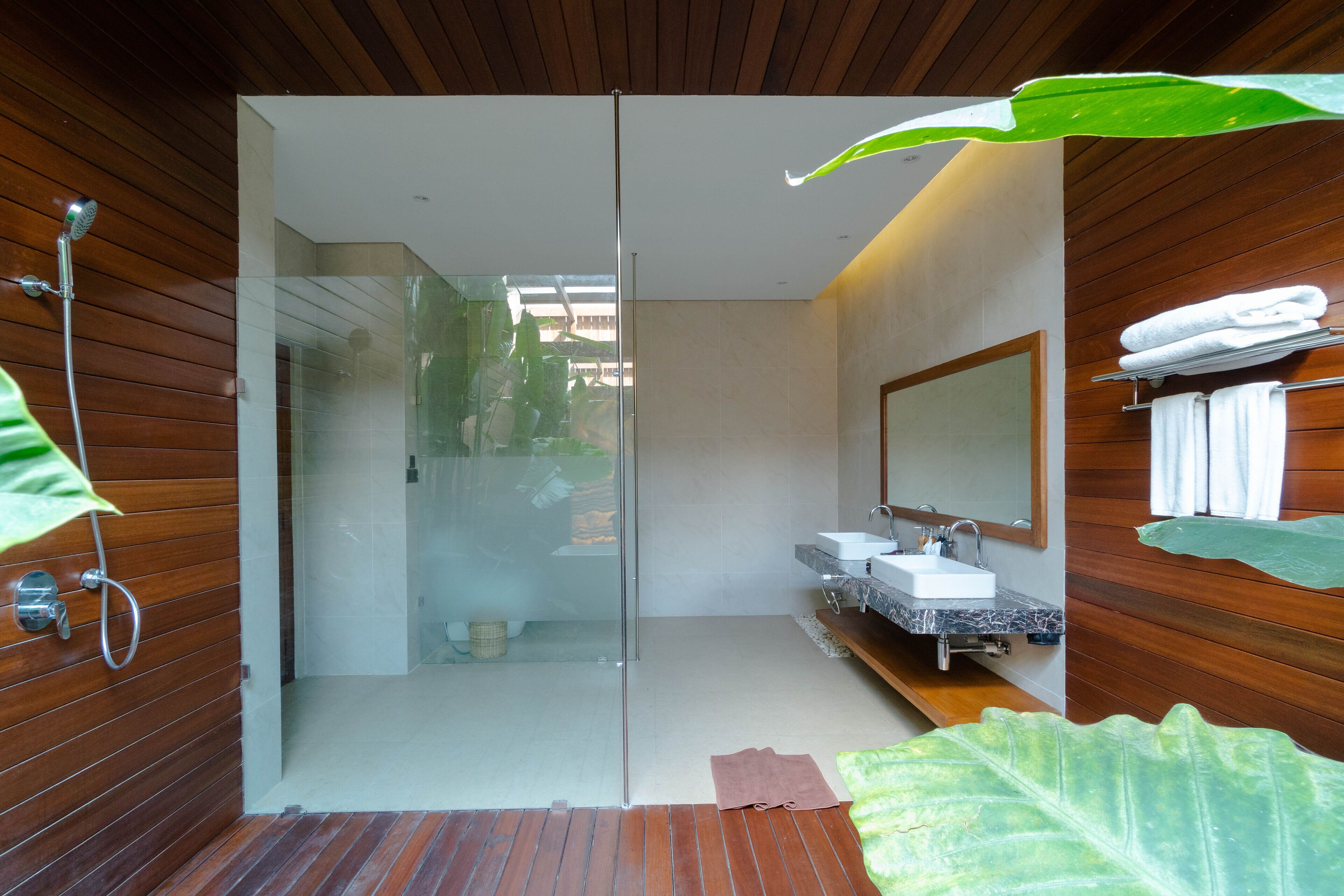 A modern bathroom with a glass shower enclosure, wooden paneling, a marble sink, and a large mirror.