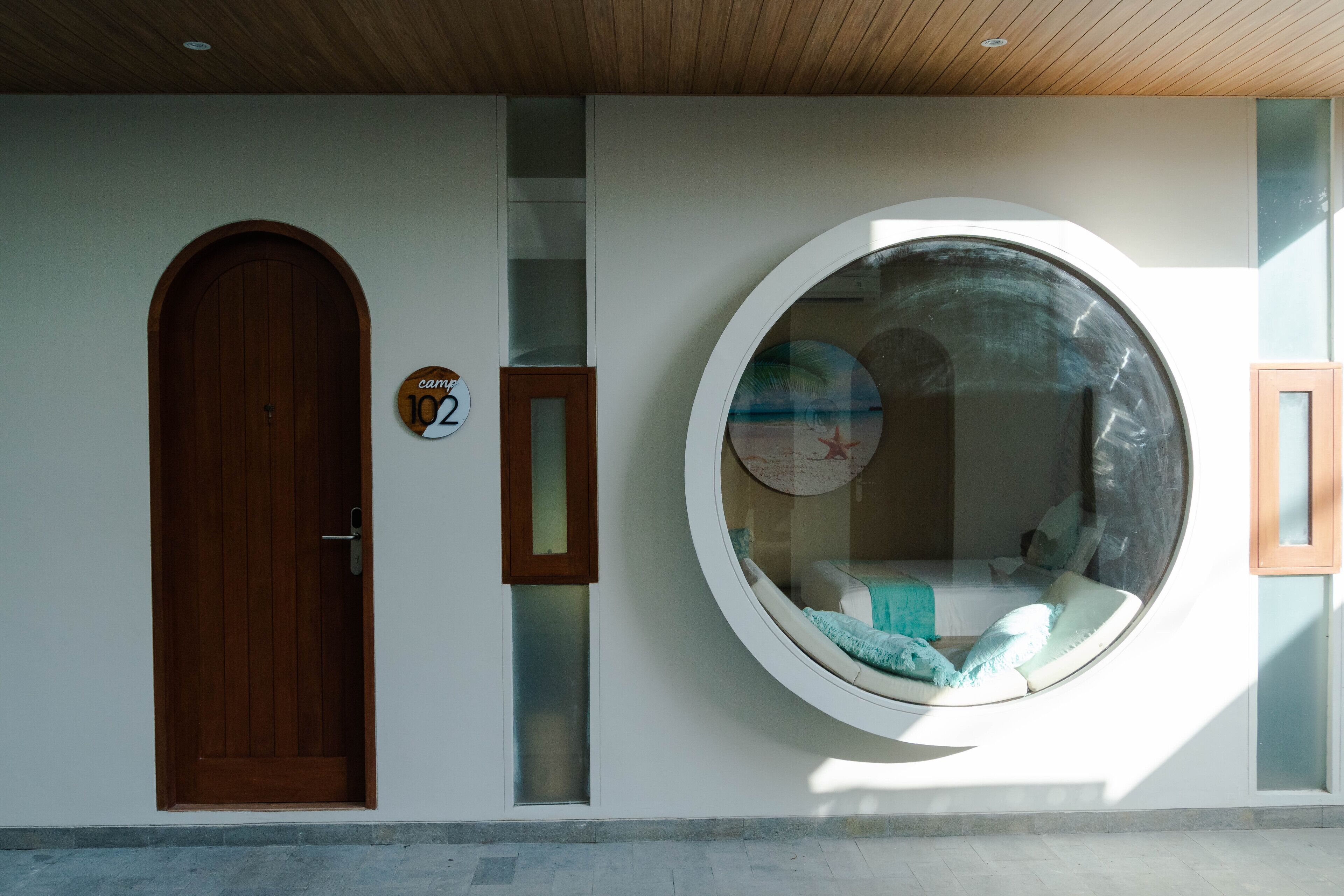 Un edificio moderno con una puerta de madera, un ventanal circular y una señal con un número.