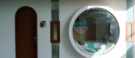 Un edificio moderno con una puerta de madera, un ventanal circular y una señal con un número.