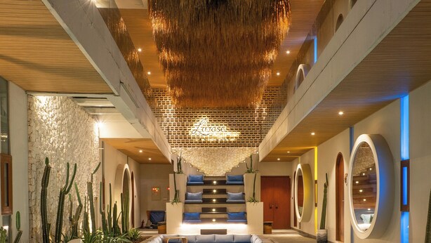 Un área de piscina interior moderna con vista despejada, asientos de descanso y una escalera que conduce a niveles superiores.