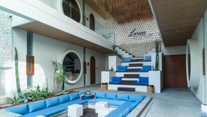 Un área exterior moderna con piscina, asientos azules y blancos y una escalera que sube a un nivel superior.