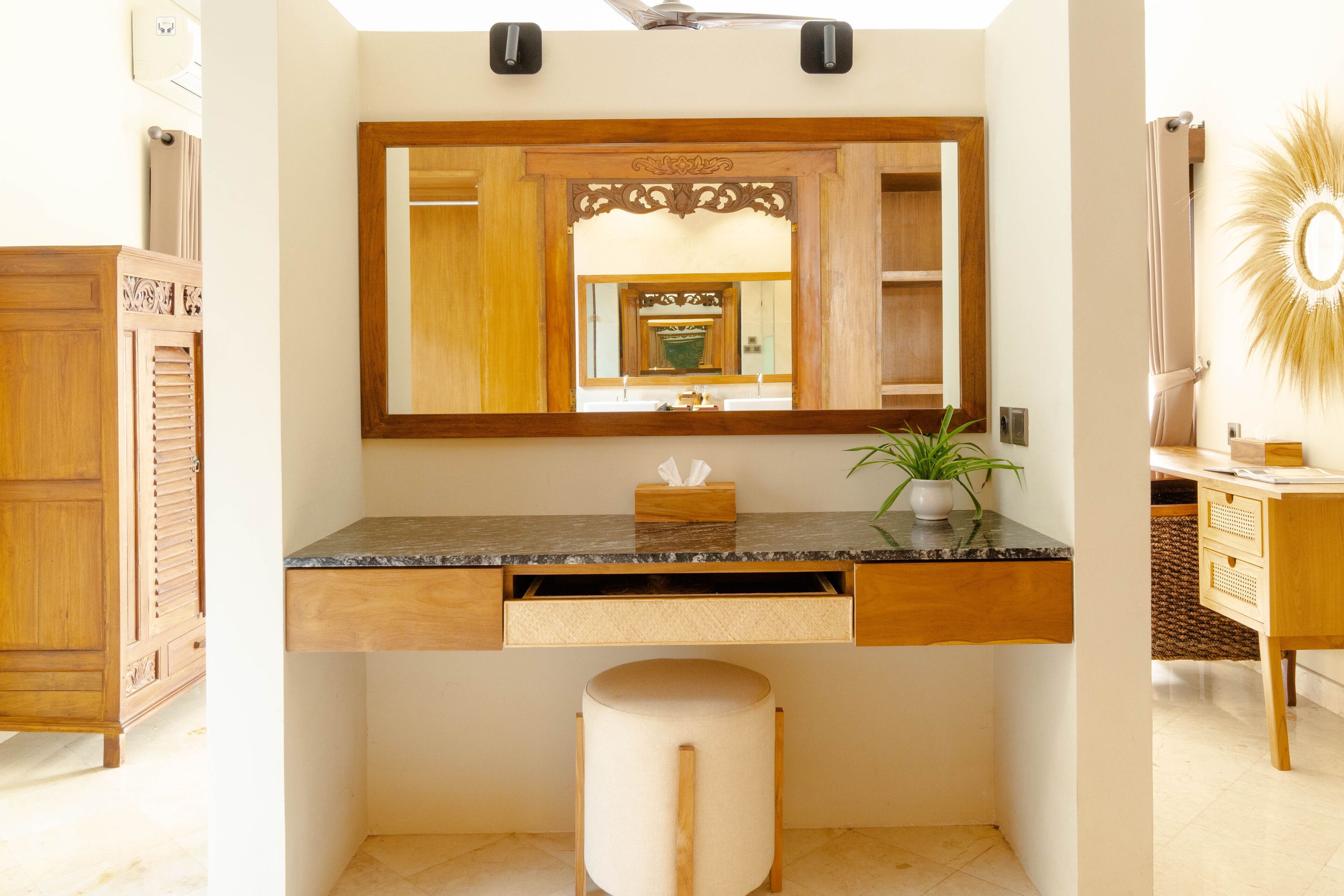 A bathroom with a wooden vanity, a mirror, a sink, a towel rack, and a potted plant.