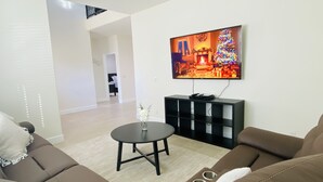 Ein modernes Wohnzimmer mit einem flachbildfernseher an der Wand, einer schwarzen Unterhaltungsecke, einem runden Couchtisch und einem braunen Ledersofa.