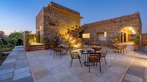 A stone building with outdoor seating and a staircase. - Sariska Courtyard by Armr Hospitality (Rajgarh)