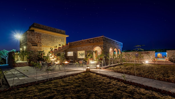A stone building with a courtyard, outdoor seating, and a water feature. - Sariska Courtyard by Armr Hospitality (Rajgarh)