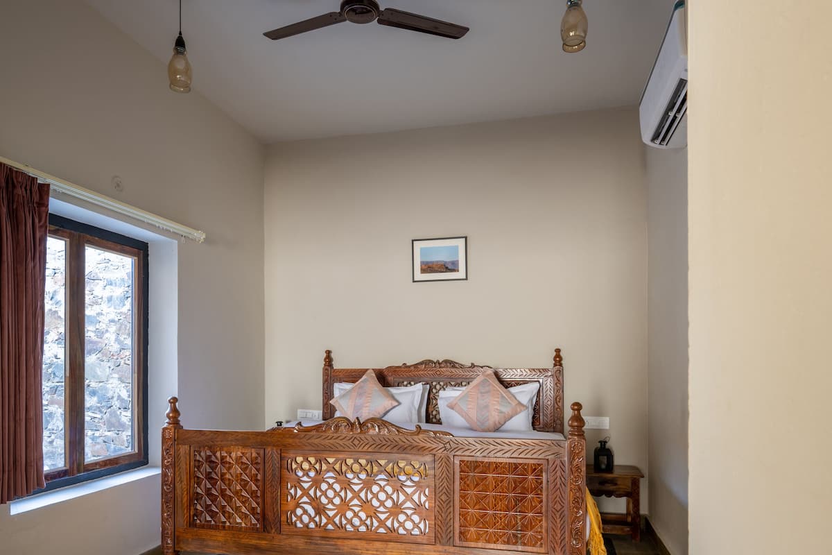Ein Schlafzimmer mit einem hölzernen Bett, einem Deckenventilator und einem Fenster mit Vorhängen.