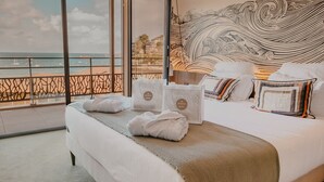 A hotel room with a large bed, a view of the sea, and a decorative wall.