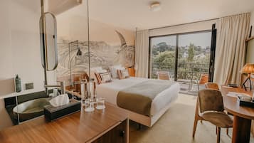 Ein Hotelzimmer mit einem großen Bett, einem Schreibtisch, einem Stuhl, einem Balkon mit Aussicht und einer Wandverkleidung.