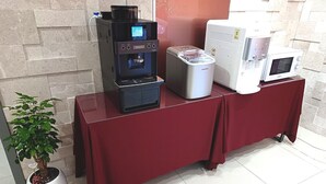 A coffee machine, a water dispenser, and a microwave on a table with a red tablecloth. - Hi&Hotel (Pyeongtaek)