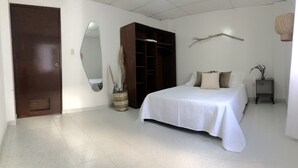 Une chambre à coucher avec un lit, une armoire, un miroir et une table de chevet.