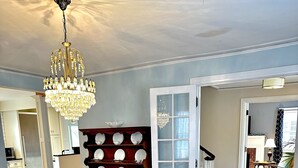 A dining area with a wooden table, chairs, a chandelier, and a china cabinet. - Historic Brick Colonial w/Amazing Kitchen- Close to downtown (Omaha)