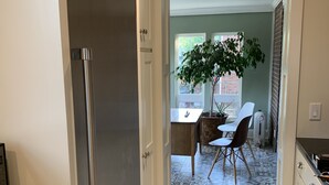 A kitchen with a stainless steel refrigerator, a dining area with a table and chairs, and a potted plant. - Historic Brick Colonial w/Amazing Kitchen- Close to downtown (Omaha)