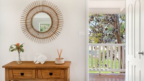A wooden console table with a mirror, a vase with a plant, and a decorative fish.