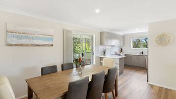 Una cocina moderna con armarios blancos, una mesa de comedor de madera y vistas al exterior.