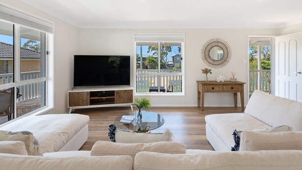 A living room with a flat-screen TV, a glass coffee table, and two sofas.