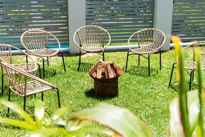 Relax in a serene outdoor space surrounded by a semi-circle of wicker chairs and a central fire pit.