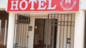 Entrada de un hotel con un llamativo letrero rojo, puertas metálicas y el número 4NG1.