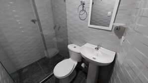 Un baño moderno con inodoro, lavamanos y cabina de ducha de vidrio.