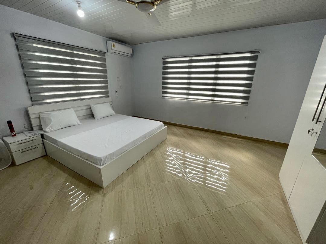 A bedroom with a bed, nightstands, a wardrobe, and a ceiling fan.