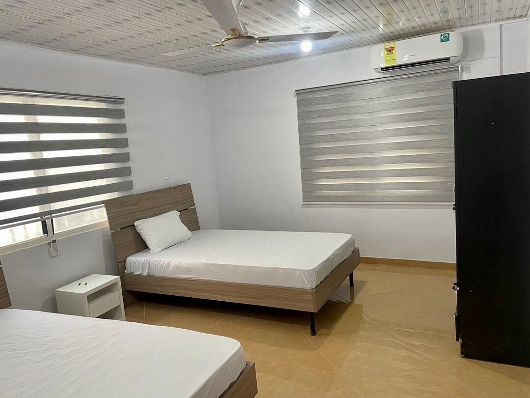 Un dormitorio con dos camas, un ventilador de techo y un equipo de aire acondicionado.