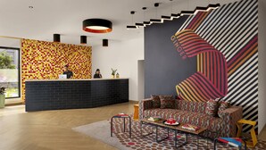 Un área de recepción moderna con pared decorada, una recepción, un sofá y una mesa de centro.