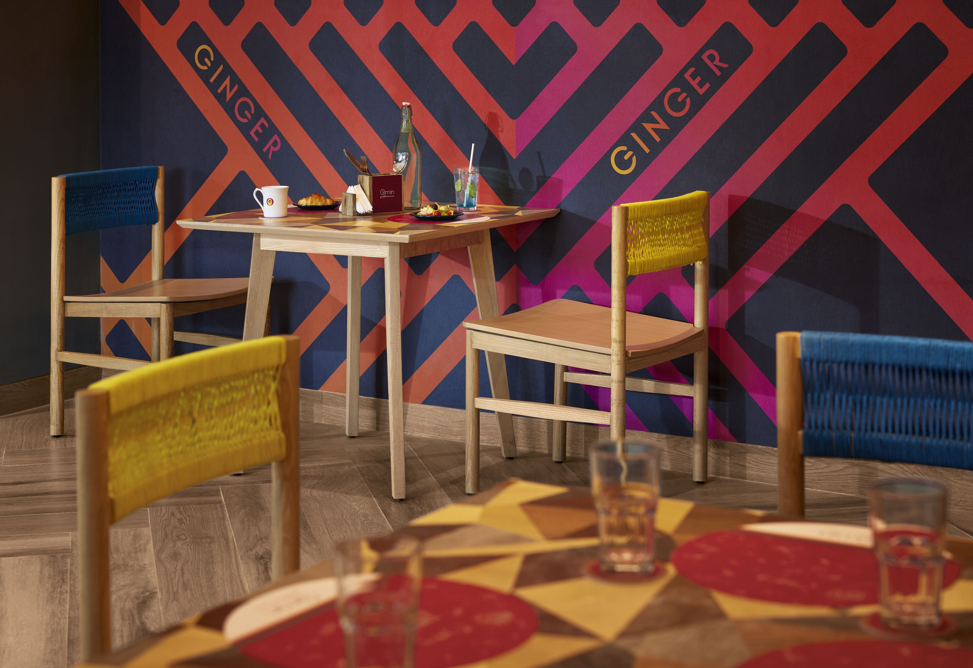 Un coin repas avec des chaises en bois et une table, une bouteille et une tasse.