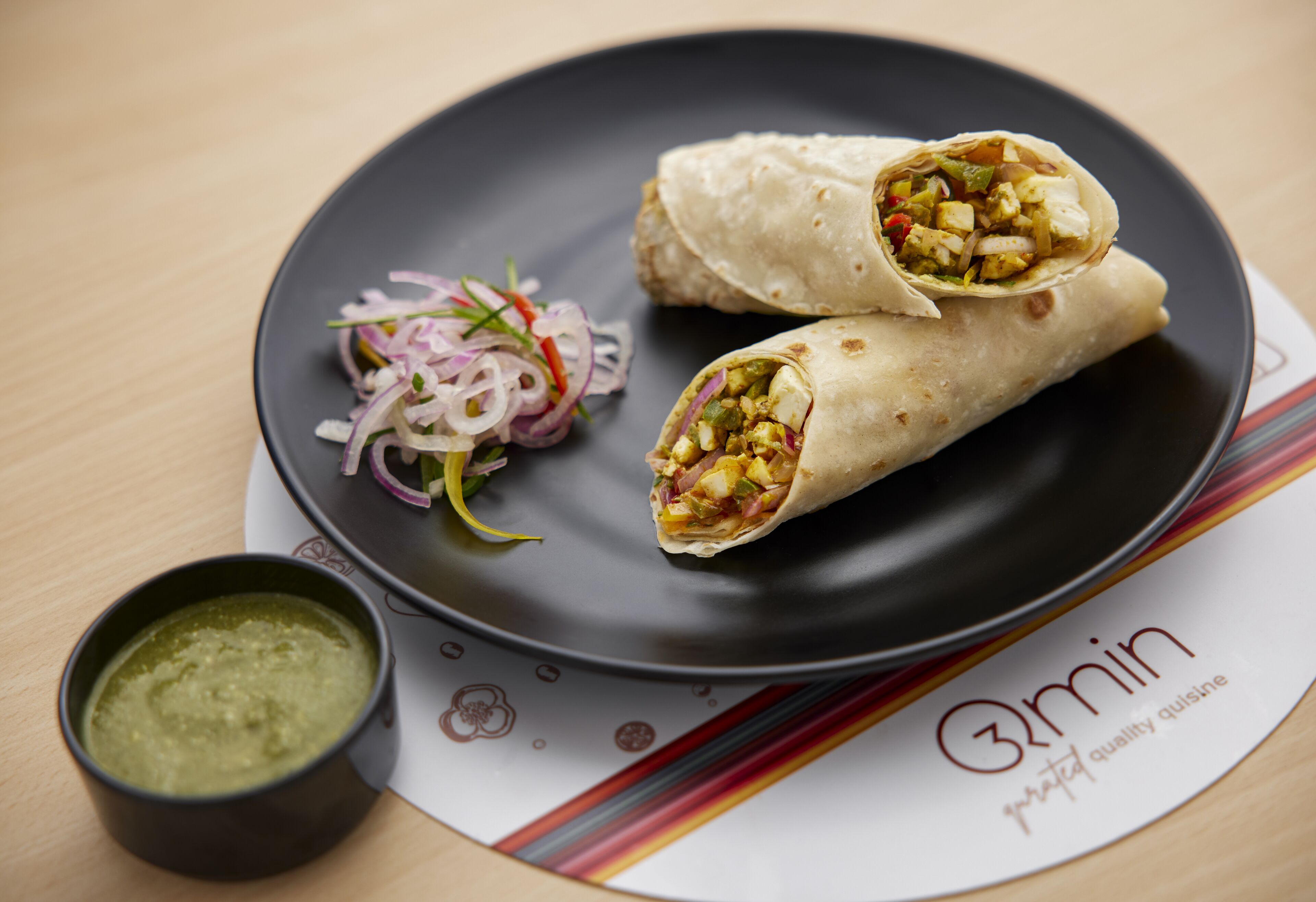 A plate with two wraps and a side salad, accompanied by a small bowl of sauce.