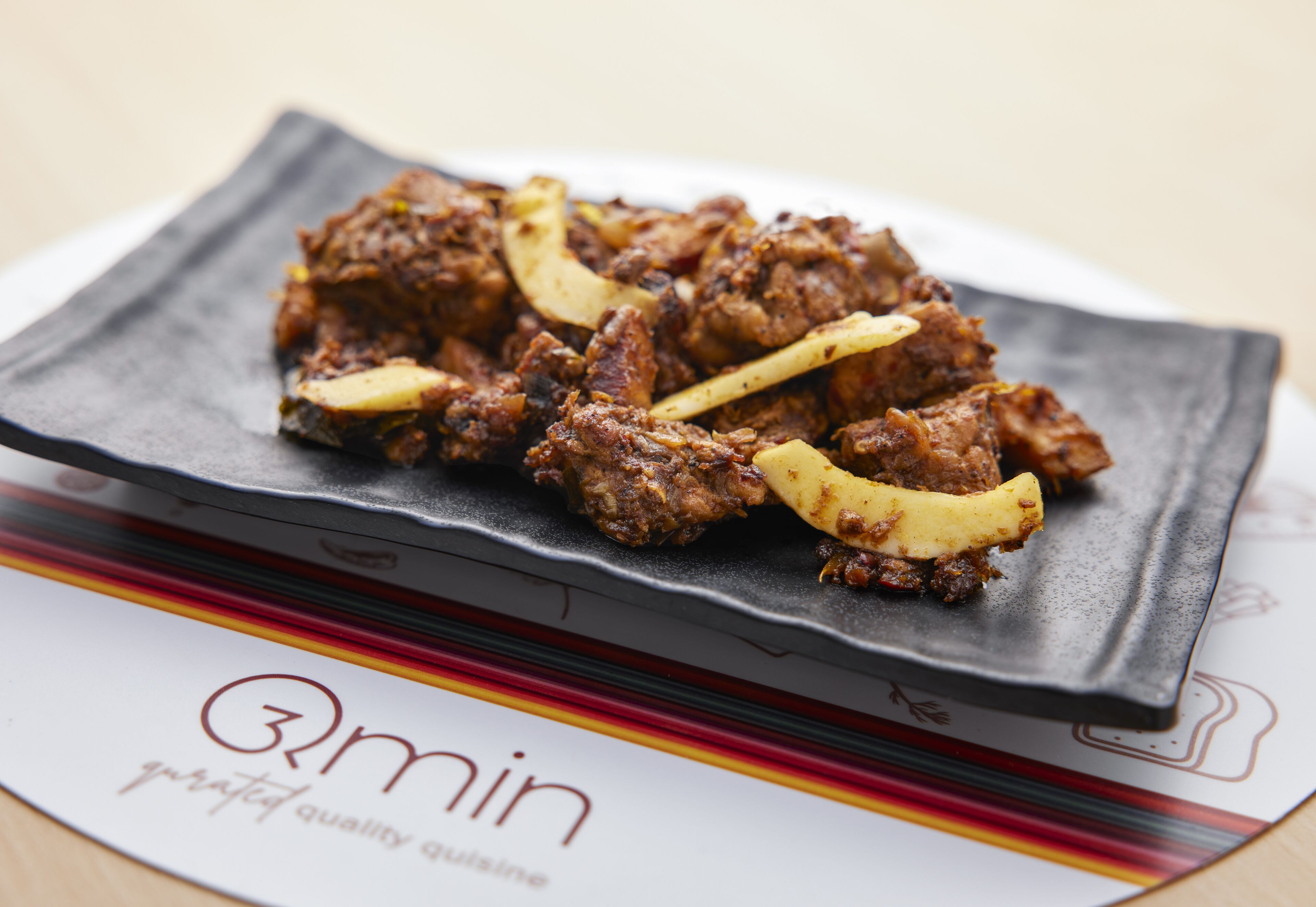 A plate of food on a black plate with a logo that reads "3min gourmet quality cuisine".