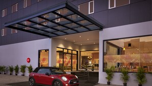 Un edificio moderno con un Mini Cooper rojo estacionado frente a él.