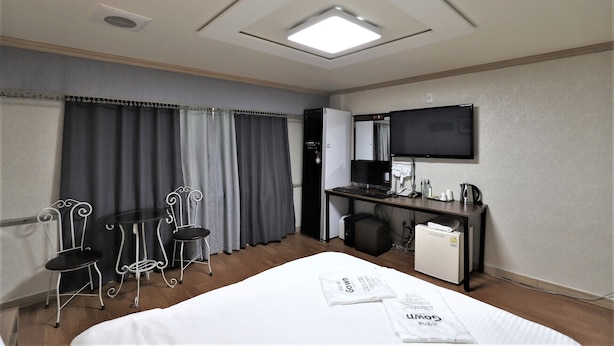 A hotel room with a bed, a desk with a computer, a TV, and a small kitchenette. - Hotel Hany (Daejeon)