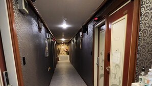 A hallway with a speckled floor, patterned walls, and doors with glass panels. - Hotel Hany (Daejeon)