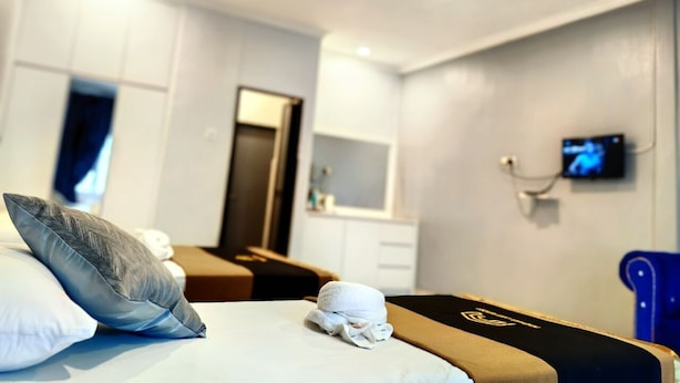 A hotel room with a bed, a massage table, a TV, and a small desk. - PendangLakeResort (Bukit Raya)