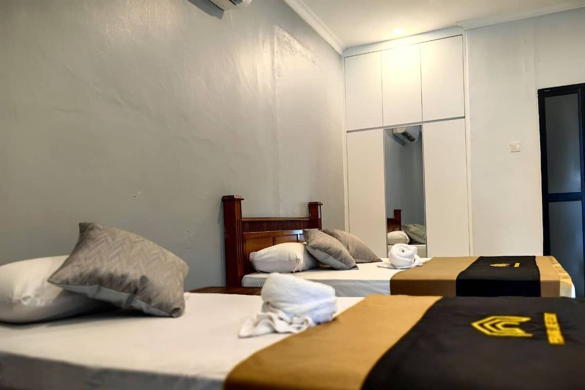 A hotel room with two beds, each with a pillow and a towel. There is a wooden headboard and a mirror on the wall.