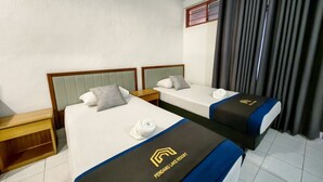 A hotel room with two beds, each with a pillow and a rolled towel. The beds have a logo on the bedspread. There is a nightstand and a window with curtains. - PendangLakeResort (Bukit Raya)