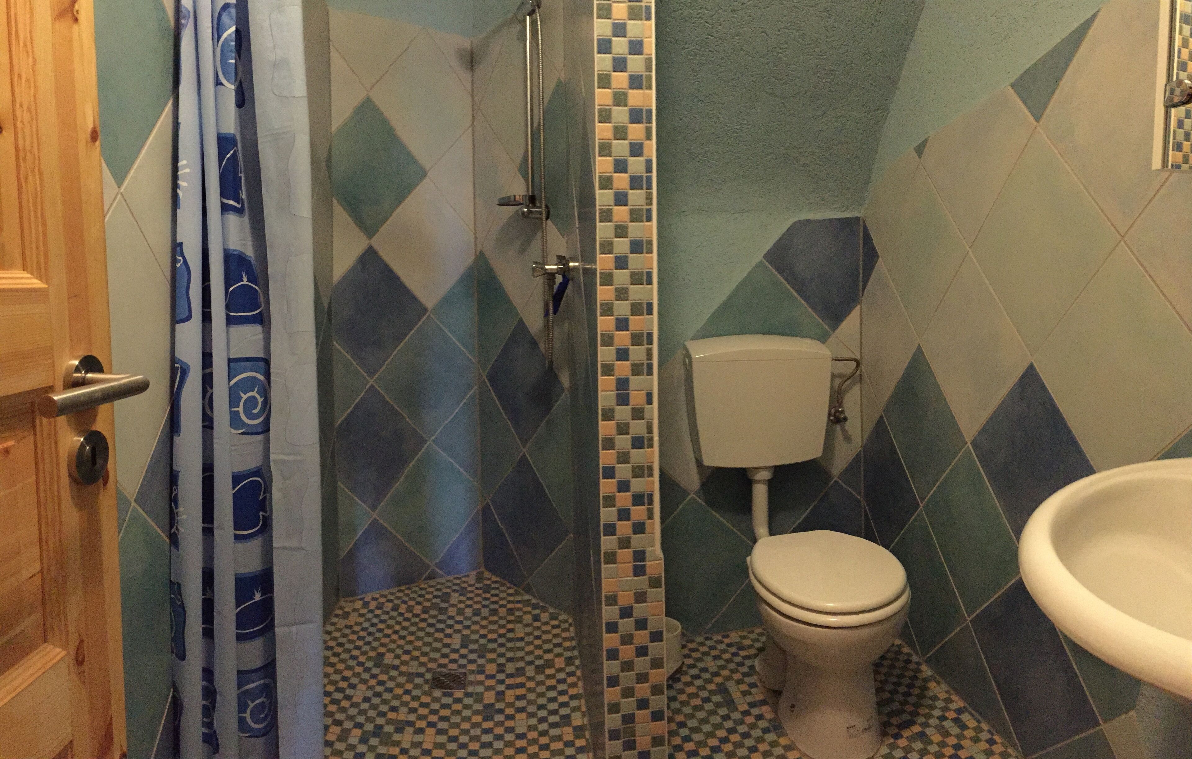 Une salle de bain avec douche, toilettes et lavabo.
